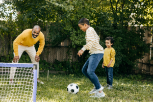 Famille jouant au football dans un jardin